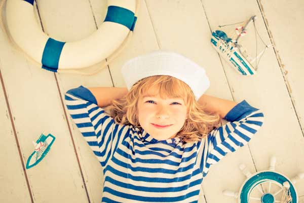 Bambino disteso sorridente vestito da marinaio