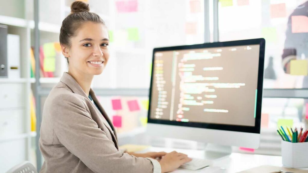 Una giovane donna programmatrice seduta davanti al proprio pc.